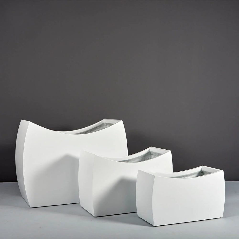 Seoul Modern Curved Rectangle Fiberglass Planter on concrete shown with three different sizes.