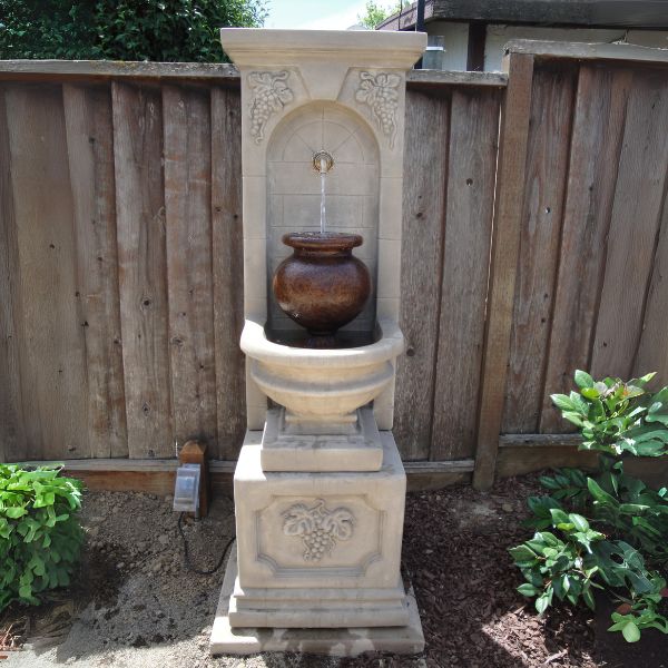 St. Helena Urn Fountain in action against wooden fence.