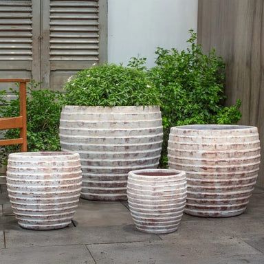 Talia Planter - Murano Sol - on concrete filled with plants.