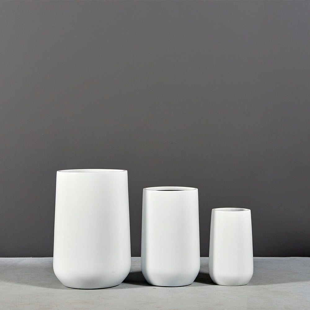 Tall Hayden Tapered Round Fiberglass Planter on concrete shown with different planter sizes.