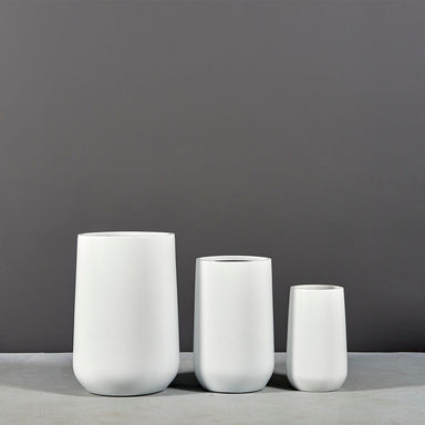 Tall Hayden Tapered Round Fiberglass Planter on concrete shown with different planter sizes.