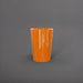 Tagel Tapered Round Fiberglass Planter in gloss tangerine against gray background.