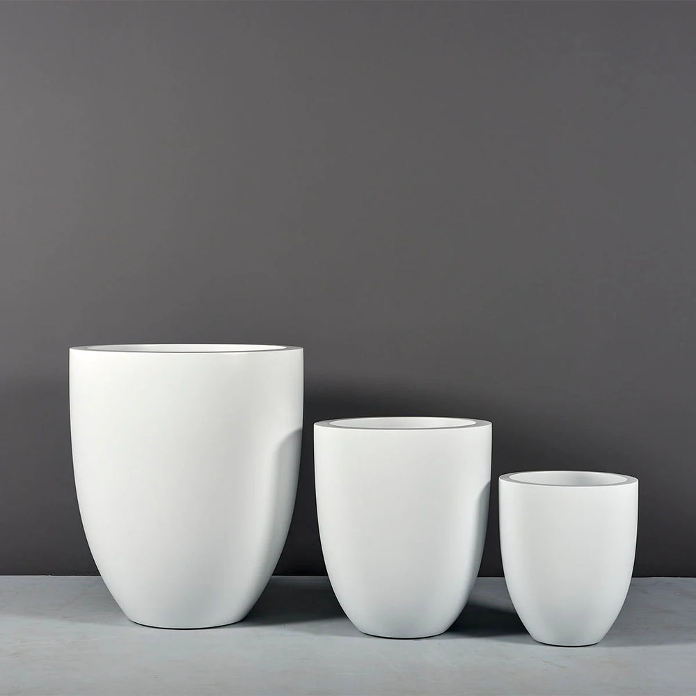Valencia Tapered Round Fiberglass Planter on concrete shown with different sizes.