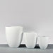 Valencia Tapered Round Fiberglass Planter on concrete shown with different sizes.