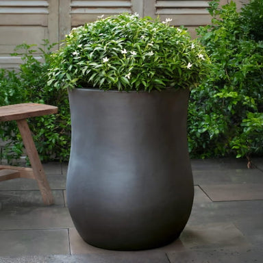 Vigneto Planter in glazed ash color on concrete filled with plants.