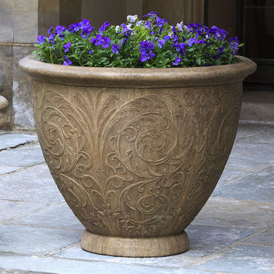 Arabesque Large Planter on concrete patio filled with purple flowers