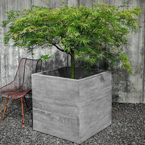 Chenes Brut Box Planter filled with plants beside a chair