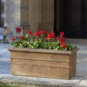 Classic Rolled Rim Window Box Planter on concrete patio filled with red flowers