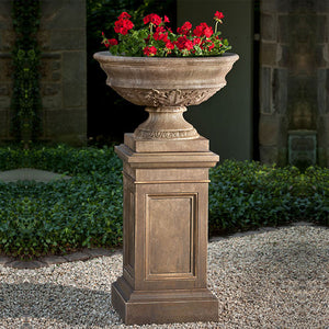 Coachhouse Urn on pedestal filled with red flowers on gravel in backyard