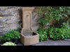 Campania Loggia Fountain on patio against wall surrounded by plants in action