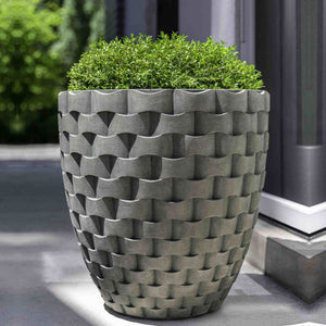 M Weave Tall Round Planter on concrete patio filled with plants