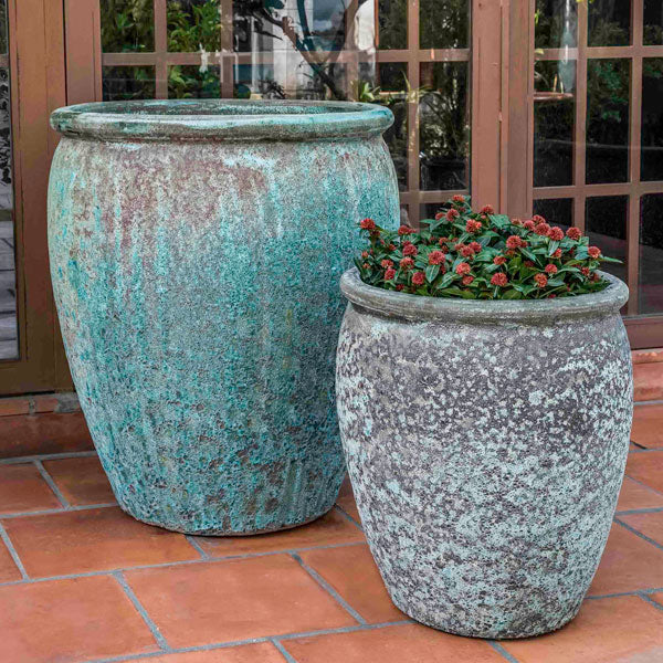 Paraiso Planter Verdigris S/2 filled with red flowers against glass door