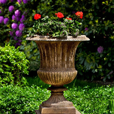 Smithsonian Classical Urn filled with red flowers in the backyard upclose