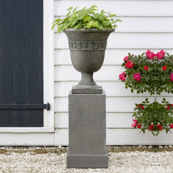 Williamsburg Strapwork Leaf Urn Planter on gravel in backyard